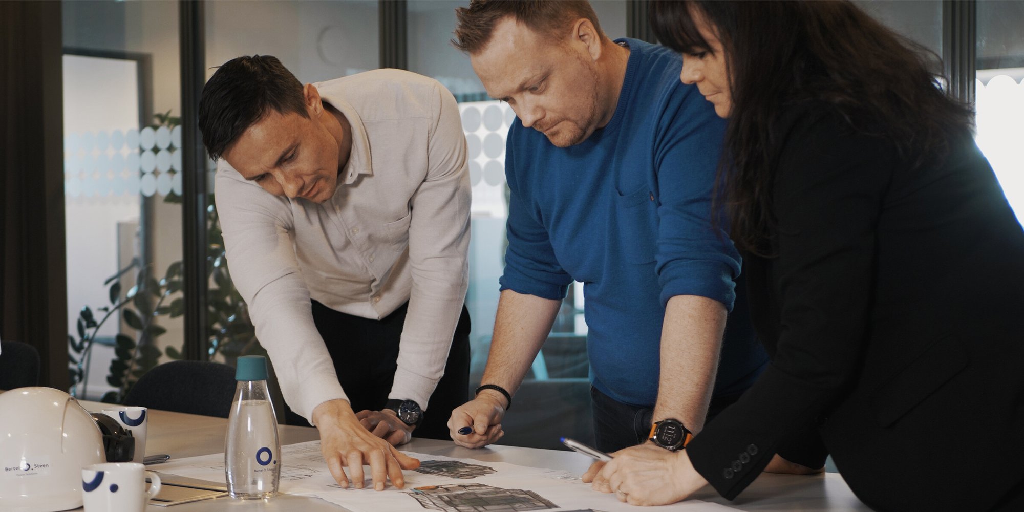 Ett team på tre personer som samarbetar kring dokument på ett kontor. Ett team på tre personer som samarbetar kring dokument på ett kontor.